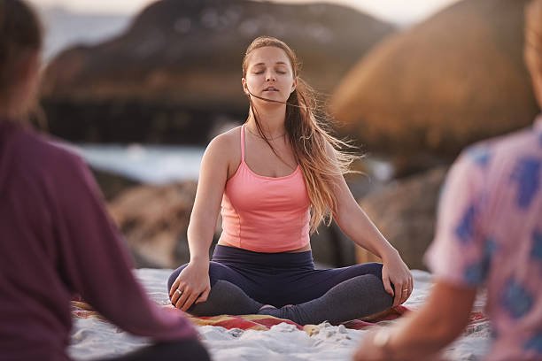 Shot of a yoga instructor giving a class on the beach